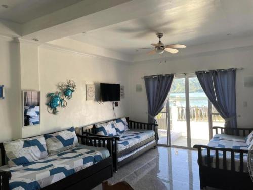 a living room with two beds and a ceiling fan at Lopez Beach Resort in Sipalay