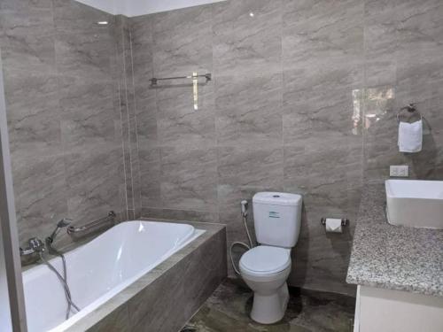 a bathroom with a tub and a toilet and a sink at Lopez Beach Resort in Sipalay