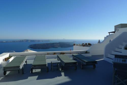 a patio with tables and chairs on the side of a building at Altana Cliffside Villas in Imerovigli