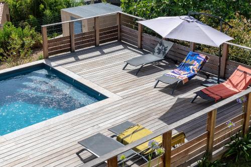 a wooden deck with a swimming pool and an umbrella at Résidence U Manellu in Santa-Reparata-di-Balagna
