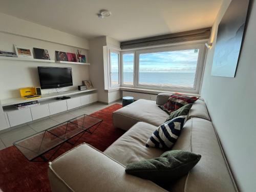 a living room with a couch and a large window at AMAZING Beach View Apartment type 28 in Ostend