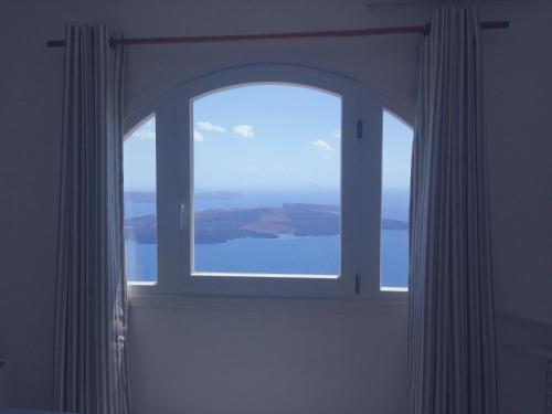 an open window with a view of the water at Altana Cliffside Villas in Imerovigli