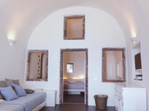 a living room with a couch and two mirrors at Altana Cliffside Villas in Imerovigli