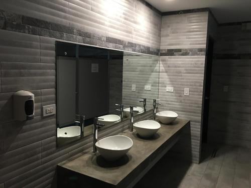 a public bathroom with three sinks and a mirror at Villa Paraiso do Mar in Jacó