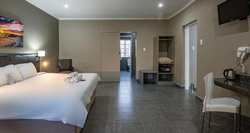 a bedroom with a large white bed and a desk at Calvinia Hotel in Calvinia