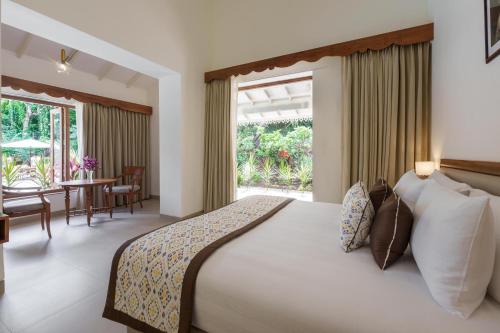 une chambre avec un grand lit et une salle à manger dans l'établissement ama Stays & Trails Palmeira De Socorro , Goa, à Vieux-Goa