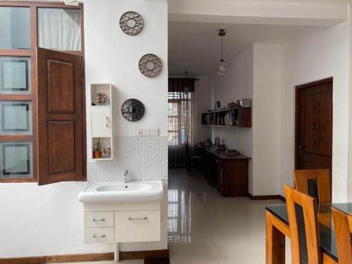 a white kitchen with a sink and a room at Luxury Apartment in Kaduwela