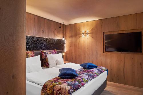 a bedroom with a bed and a tv on a wall at Sporthotel Ellmau in Tirol in Ellmau