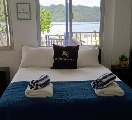 a bed with towels on it with a large window at Lopez Beach Resort in Sipalay