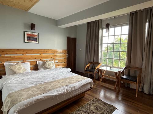 a bedroom with a bed and a desk and a window at Bahar Retreat And Spa , Gangtok in Gangtok