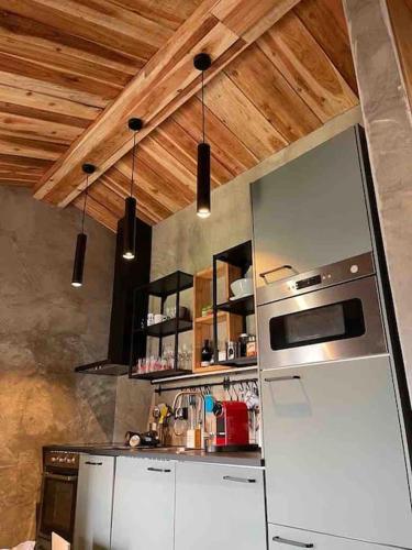 a kitchen with a white refrigerator and a wooden ceiling at Casa da Esquila Ilha do Pico 2 in Cais do Pico