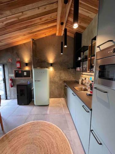 a kitchen with a white refrigerator and a sink at Casa da Esquila Ilha do Pico 2 in Cais do Pico