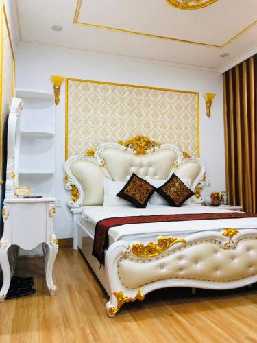 a bedroom with a white bed with a gold and white headboard at LAS VEGAS HOTEL in Quang Ninh