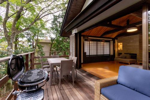 a porch with a grill and a table and chairs at Hakone Sengokuhara Soubokuan 箱根仙石原 相睦菴 in Sengokuhara