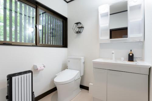a white bathroom with a toilet and a sink at Hakone Sengokuhara Soubokuan 箱根仙石原 相睦菴 in Sengokuhara