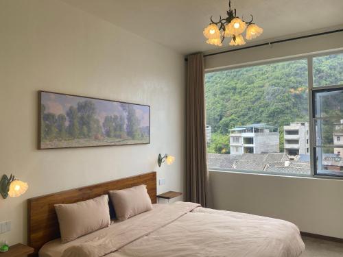 a bedroom with a bed and a large window at Pomelo Hostel in Yangshuo