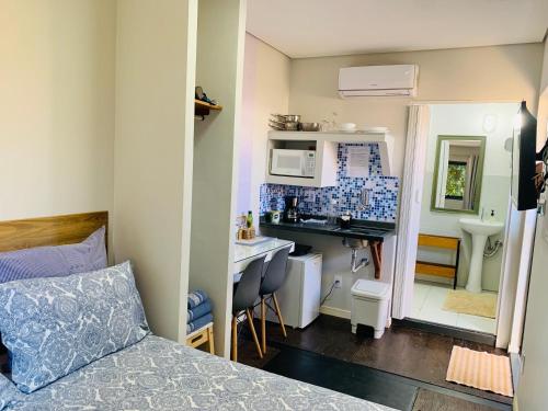 a small room with a bed and a kitchen at Maritimus Suítes in Barretos