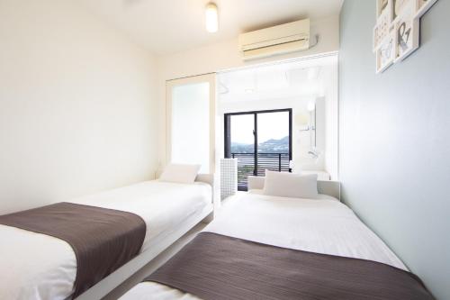 two beds in a room with a window at HOTEL E-horizon Resort コンドミニアム瀬底 in Motobu
