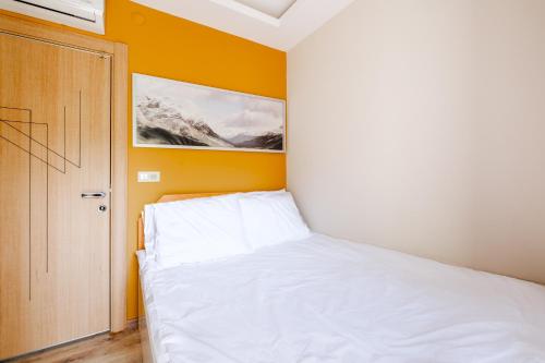 a bedroom with a white bed and a yellow wall at Flat w Balcony 5 min to Beach in Kemer in Antalya