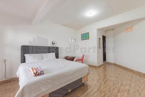 a bedroom with a large bed and a red chair at Pondok Hefi Ciwidey Mitra RedDoorz in Ciwidey
