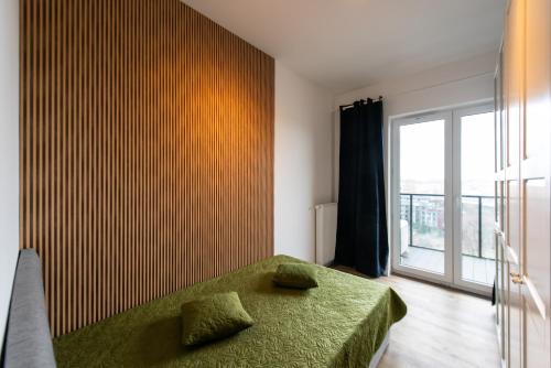 a bedroom with a green bed and a large window at Apartament River Towers in Bydgoszcz