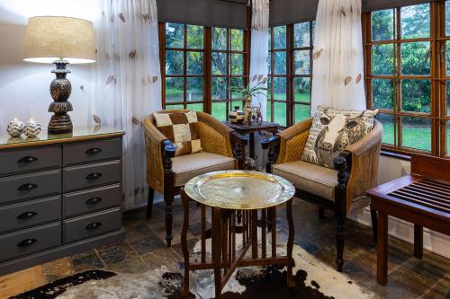 a living room with a table and two chairs and a piano at Seaforth Country House in Ballito