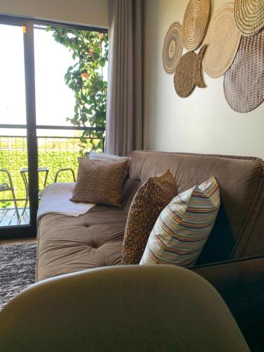 a living room with a brown couch with pillows at Maritimus Suites Apartamento 07 in Barretos