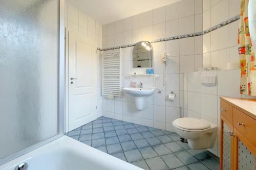 a bathroom with a tub and a toilet and a sink at Jägerstrasse 7 Ferienwohnung 8 in Kölpinsee