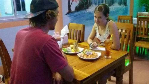 a man and a woman sitting at a table eating food at Peace Lanta Mansion in Ko Lanta