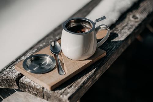 a cup of coffee and a spoon on a wooden tray at Alpenappartements Cristall in Ehrwald