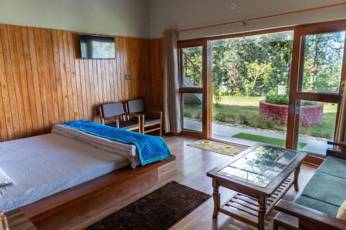 a bedroom with a bed and a glass table at THE HIMALAYAN WOODS, CHAUKORI in Chaukori