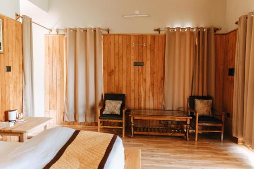 a bedroom with a bed and two chairs and a table at THE HIMALAYAN WOODS, CHAUKORI in Chaukori