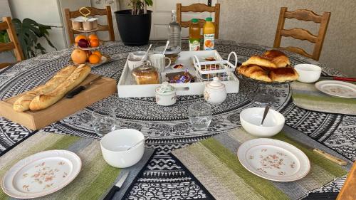 a table with a plate of food and bread on it at Chambres Quiétude in Chavanoz