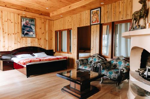 a bedroom with a bed and a couch and a table at THE HIMALAYAN WOODS, CHAUKORI in Chaukori