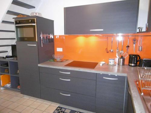 a kitchen with a counter with an orange wall at Maisonnette JIKEL à 50 m de la plage in Sarzeau