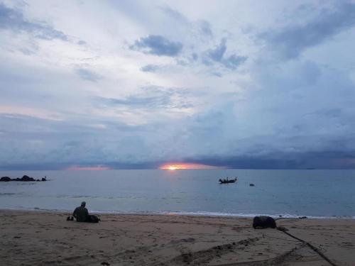 a man sitting on the beach near the water at Peace Lanta Mansion in Ko Lanta