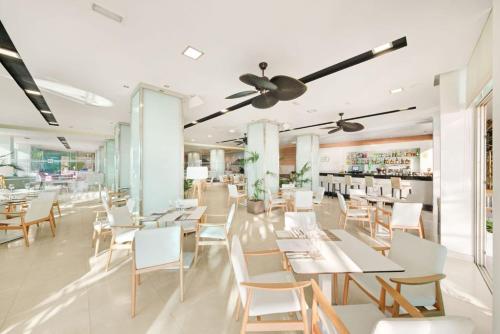 una sala da pranzo con tavoli e sedie bianchi di Hotel Agua Beach "Adults only" a Palmanova