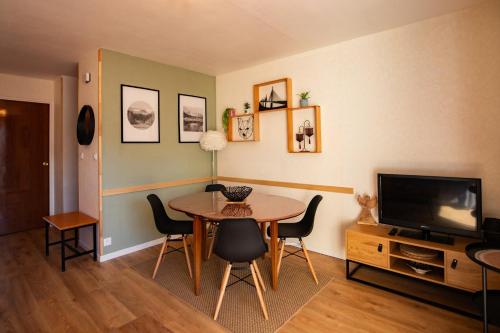 a dining room with a table and chairs and a television at La Forêt Mountain views Parking in Font-Romeu-Odeillo-Via