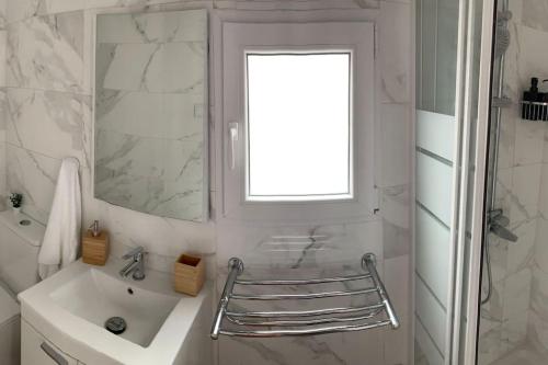 ein weißes Badezimmer mit einem Waschbecken und einem Spiegel in der Unterkunft Cozy 3bd near vibrant Valencia in Paiporta