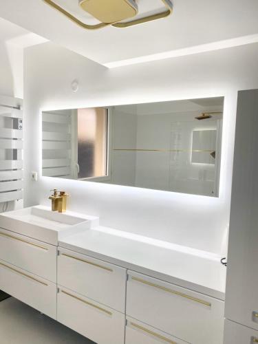 uma casa de banho branca com um lavatório e um espelho em Stylish Apartment Disneyland Paris em Chessy