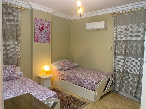 a bedroom with two beds and a table and curtains at Nile view in Cairo