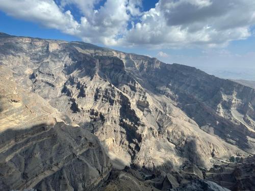 an aerial view of a rocky mountain under a cloudy sky at Jabal Shams, the summit house in Misfāh