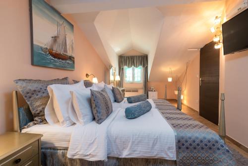 a bedroom with a large white bed with blue pillows at Heritage Hotel Pasike in Trogir