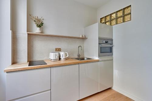 une cuisine avec des armoires blanches et un évier dans l'établissement Sublime studio Beaubourg by Studio prestige, à Paris
