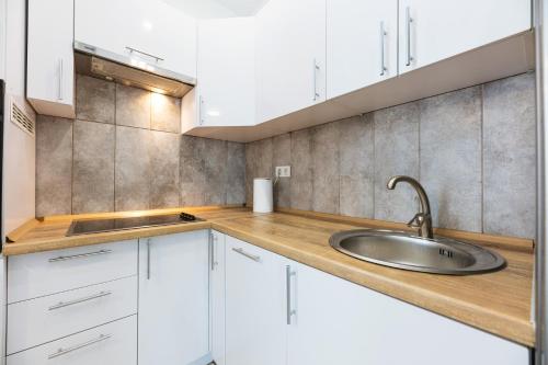a kitchen with white cabinets and a sink at Nyvky Brown in Kyiv