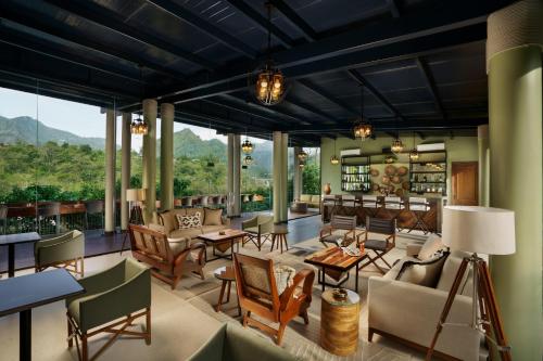 a living room with chairs and tables and windows at Anand Kashi by the Ganges Rishikesh - IHCL Seleqtions in Rishīkesh