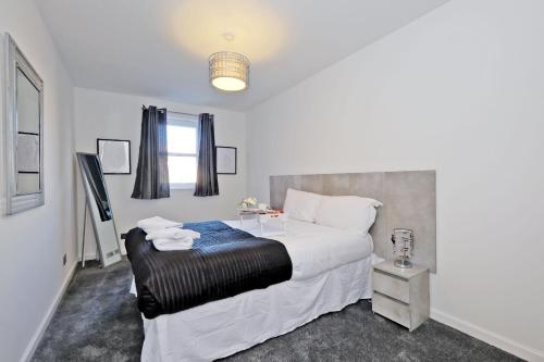 a bedroom with a large white bed and a table at Orange Apartments Belgrave Mansions in Aberdeen