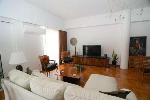 uma sala de estar com um sofá branco e uma televisão em Φωτεινό κομψό & άνετο διαμέρισμα κοντά στο κέντρο! em Atenas