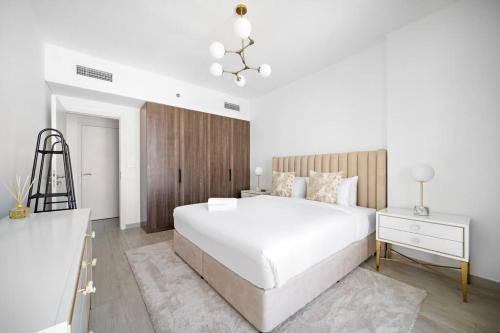 Un dormitorio blanco con una gran cama blanca y una mesa en Chic 1BR APT Rahaal 2 MJL, en Dubái