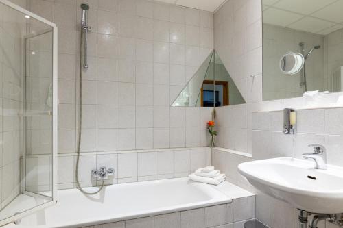 a white bathroom with a shower and a sink at Residenz Royal in Sandhausen